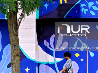 A person is walking in front of a colorful mural near the downtown Brampton, Ontario, transit terminal on Monday, August 5, 2024. (