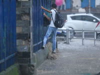 A man is taking support of the railings to get across the flooded section of road in Kathmandu, Nepal, on August 6, 2024. Nepal's Meteorolog...