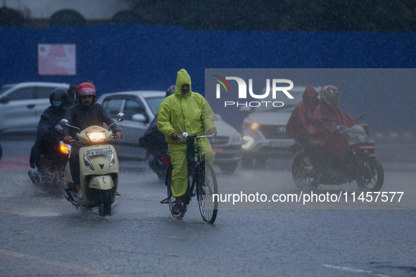 A cyclist is wearing a raincoat and pedaling through the flooded streets of Kathmandu, Nepal, on August 6, 2024. Nepal's Meteorological Fore...