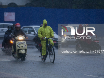 A cyclist is wearing a raincoat and pedaling through the flooded streets of Kathmandu, Nepal, on August 6, 2024. Nepal's Meteorological Fore...