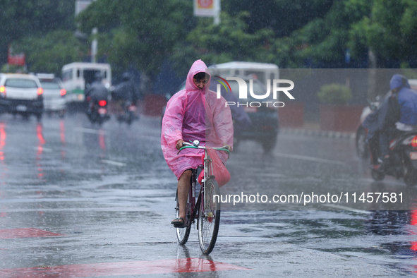 A cyclist is wearing a raincoat and pedaling through the flooded streets of Kathmandu, Nepal, on August 6, 2024. Nepal's Meteorological Fore...