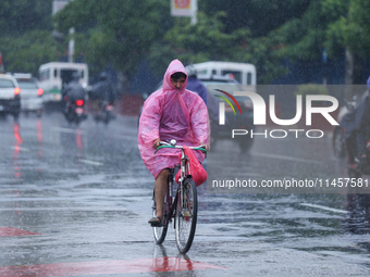 A cyclist is wearing a raincoat and pedaling through the flooded streets of Kathmandu, Nepal, on August 6, 2024. Nepal's Meteorological Fore...