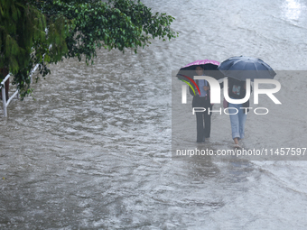 People are wading through flooded roads in Kathmandu, Nepal, on August 6, 2024. Nepal's Meteorological Forecasting Division (MFD) under the...