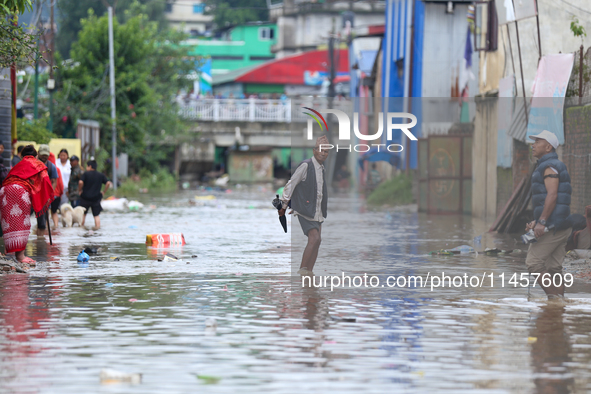 People are wading through flood water carrying their belongings and other items of necessity in Kathmandu, Nepal, on August 6, 2024. Nepal's...