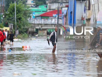 People are wading through flood water carrying their belongings and other items of necessity in Kathmandu, Nepal, on August 6, 2024. Nepal's...