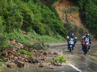 Motorcyclists are driving next to the landslide that came down in Chovar of Kathmandu, Nepal, on August 6, 2024, after incessant rainfall ov...