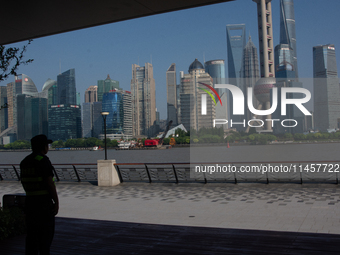 A security worker is protecting under the shadow in North Bund, Shanghai, China, on August 6, 2024. (