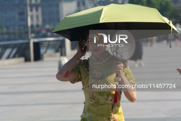 A woman is protecting herself with an umbrella from the sun at the Bund in Shanghai, China, on August 6, 2024. 