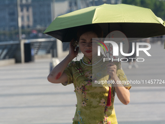 A woman is protecting herself with an umbrella from the sun at the Bund in Shanghai, China, on August 6, 2024. (