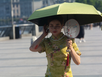 A woman is protecting herself with an umbrella from the sun at the Bund in Shanghai, China, on August 6, 2024. (