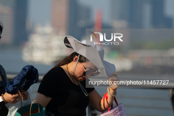 A woman is shielding herself from the sun at Bund in Shanghai, China, on August 6, 2024. 