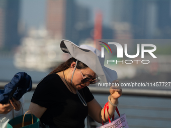 A woman is shielding herself from the sun at Bund in Shanghai, China, on August 6, 2024. (