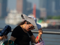 A woman is shielding herself from the sun at Bund in Shanghai, China, on August 6, 2024. (