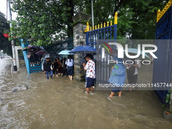 People are wading through flooded roads in Kathmandu, Nepal, on August 6, 2024. Nepal's Meteorological Forecasting Division (MFD) under the...