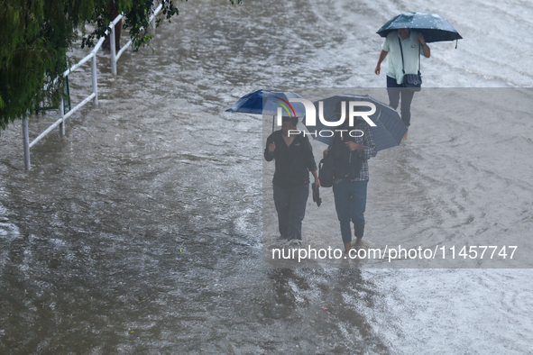 People are wading through flooded roads in Kathmandu, Nepal, on August 6, 2024. Nepal's Meteorological Forecasting Division (MFD) under the...