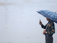 A man is taking a photo on his phone, recording the swollen Bagmati River on the embankments of Bagmati River in Teku of Kathmandu, Nepal, o...