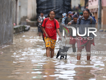 People are wading through flood water carrying their belongings and other items of necessity in Kathmandu, Nepal, on August 6, 2024. Nepal's...