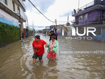 People are wading through flood water carrying their belongings and other items of necessity in Kathmandu, Nepal, on August 6, 2024. Nepal's...