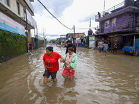 People are wading through flood water carrying their belongings and other items of necessity in Kathmandu, Nepal, on August 6, 2024. Nepal's...