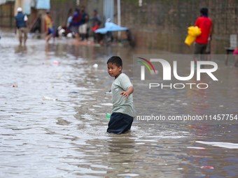 A boy is wading through flooded water on the embankments of Bagmati River in Balkhu of Kathmandu, Nepal, on August 6, 2024. Nepal's Meteorol...