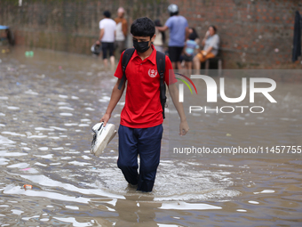 A boy is wading through flooded water on the embankments of Bagmati River in Balkhu of Kathmandu, Nepal, on August 6, 2024. Nepal's Meteorol...