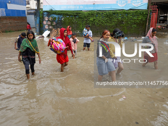 People are wading through flood water carrying their belongings and other items of necessity in Kathmandu, Nepal, on August 6, 2024. Nepal's...