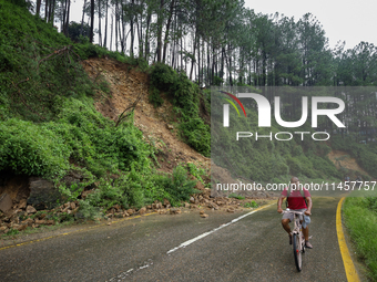 A cyclist is pedaling next to the landslide that came down in Chovar of Kathmandu, Nepal, on August 6, 2024, after incessant rainfall overni...