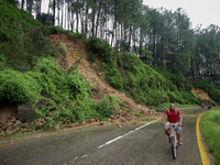 A cyclist is pedaling next to the landslide that came down in Chovar of Kathmandu, Nepal, on August 6, 2024, after incessant rainfall overni...