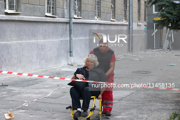 A paramedic is pushing an injured woman in an evacuation chair to an ambulance after the Russian rocket attack in Kharkiv, Ukraine, on Augus...