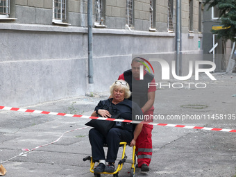 A paramedic is pushing an injured woman in an evacuation chair to an ambulance after the Russian rocket attack in Kharkiv, Ukraine, on Augus...