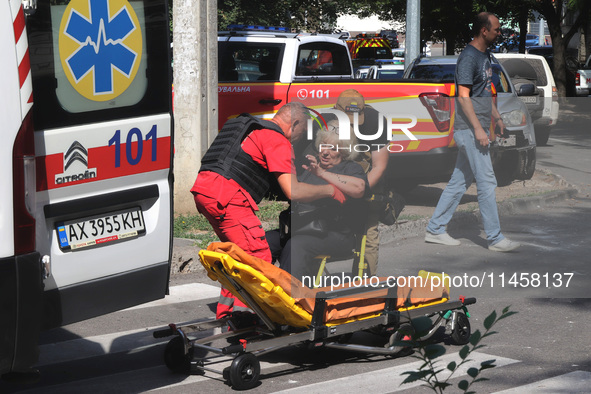 A paramedic and a man are helping an injured woman get onto a stretcher by an ambulance after the Russian rocket attack in Kharkiv, Ukraine,...