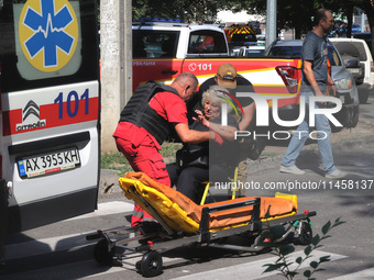 A paramedic and a man are helping an injured woman get onto a stretcher by an ambulance after the Russian rocket attack in Kharkiv, Ukraine,...