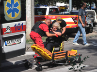 A paramedic and a man are helping an injured woman get onto a stretcher by an ambulance after the Russian rocket attack in Kharkiv, Ukraine,...