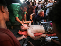 Palestinian medics are transporting an injured person following Israeli bombardment on Deir el-Balah into the Al-Aqsa Martyrs hospital in th...