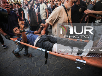 Palestinian medics are transporting an injured person following Israeli bombardment on Deir el-Balah into the Al-Aqsa Martyrs hospital in th...