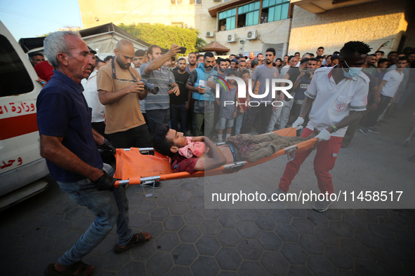 Palestinian medics are transporting an injured person following Israeli bombardment on Deir el-Balah into the Al-Aqsa Martyrs hospital in th...