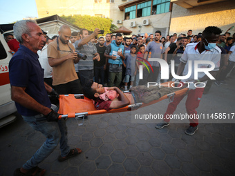 Palestinian medics are transporting an injured person following Israeli bombardment on Deir el-Balah into the Al-Aqsa Martyrs hospital in th...