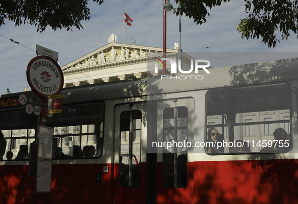 Passengers ride a tram past the Austrian Parliament in central Vienna early in the morning. Austria, Wednesday, August 7, 2024. 