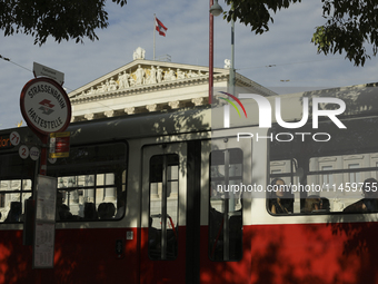 Passengers ride a tram past the Austrian Parliament in central Vienna early in the morning. Austria, Wednesday, August 7, 2024. (