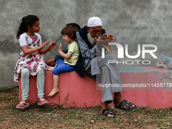 An elderly man is raising his hands during supplication as kids are playing while Muslim devotees (not in picture) are taking part in Salatu...