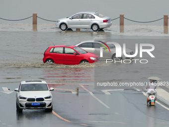 Vehicles are passing a waterlogged section of Binhai Middle Road in Yantai, China, on August 6, 2024. (