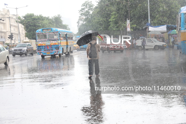 A man is crossing a busy road with an umbrella during heavy monsoon rain in Kolkata, India, on July 07, 2024. 