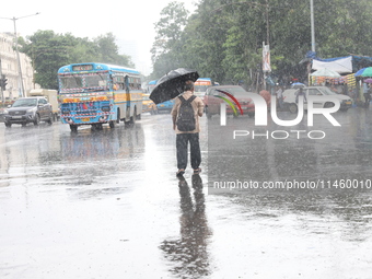 A man is crossing a busy road with an umbrella during heavy monsoon rain in Kolkata, India, on July 07, 2024. (