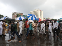 Police officers are holding umbrellas as commuters are walking past during monsoon rain in Kolkata, India, on July 07, 2024. (