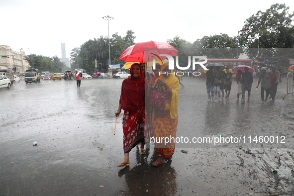 Women are walking on a road with an umbrella during heavy monsoon rain in Kolkata, India, on July 07, 2024. 