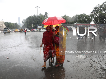 Women are walking on a road with an umbrella during heavy monsoon rain in Kolkata, India, on July 07, 2024. (