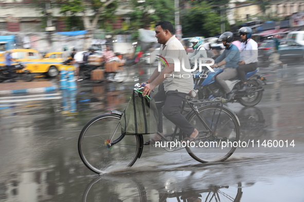 A man is riding his bicycle during heavy monsoon rain in Kolkata, India, on July 07, 2024. 