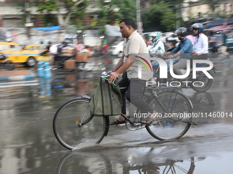 A man is riding his bicycle during heavy monsoon rain in Kolkata, India, on July 07, 2024. (