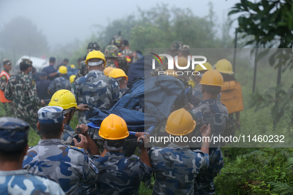 Nepali security forces are carrying the bodies of victims to the hearse from the site of the crashed Air Dynasty Helicopter in Nuwakot Distr...