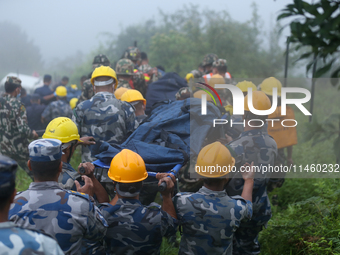 Nepali security forces are carrying the bodies of victims to the hearse from the site of the crashed Air Dynasty Helicopter in Nuwakot Distr...